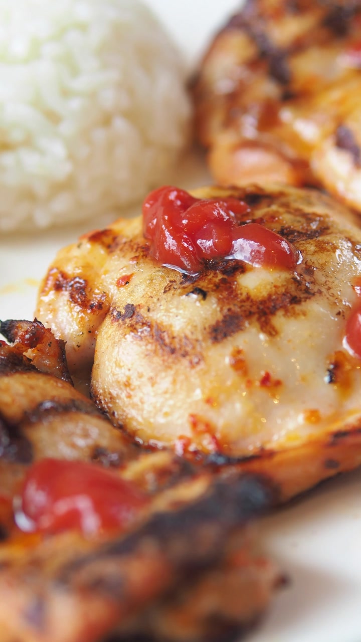 Close-up of Grilled Chicken with Ketchup and Rice on a Plate