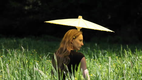 a young woman with an umbrella standing in tall grass