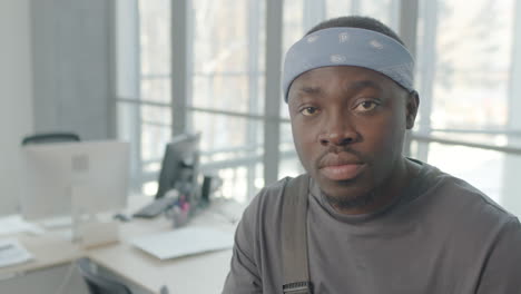 close up view of cleaning man wearing bandana looking at the camera inside an office