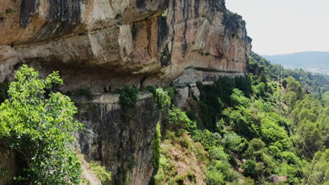 Tilt-down-shot-of-a-sandstone-hill-and-Mirador-el-Puente-Romano-road-in-it