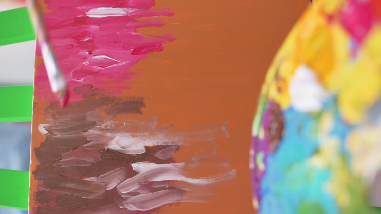 A woman painting a picture using a palette and brush in a studio