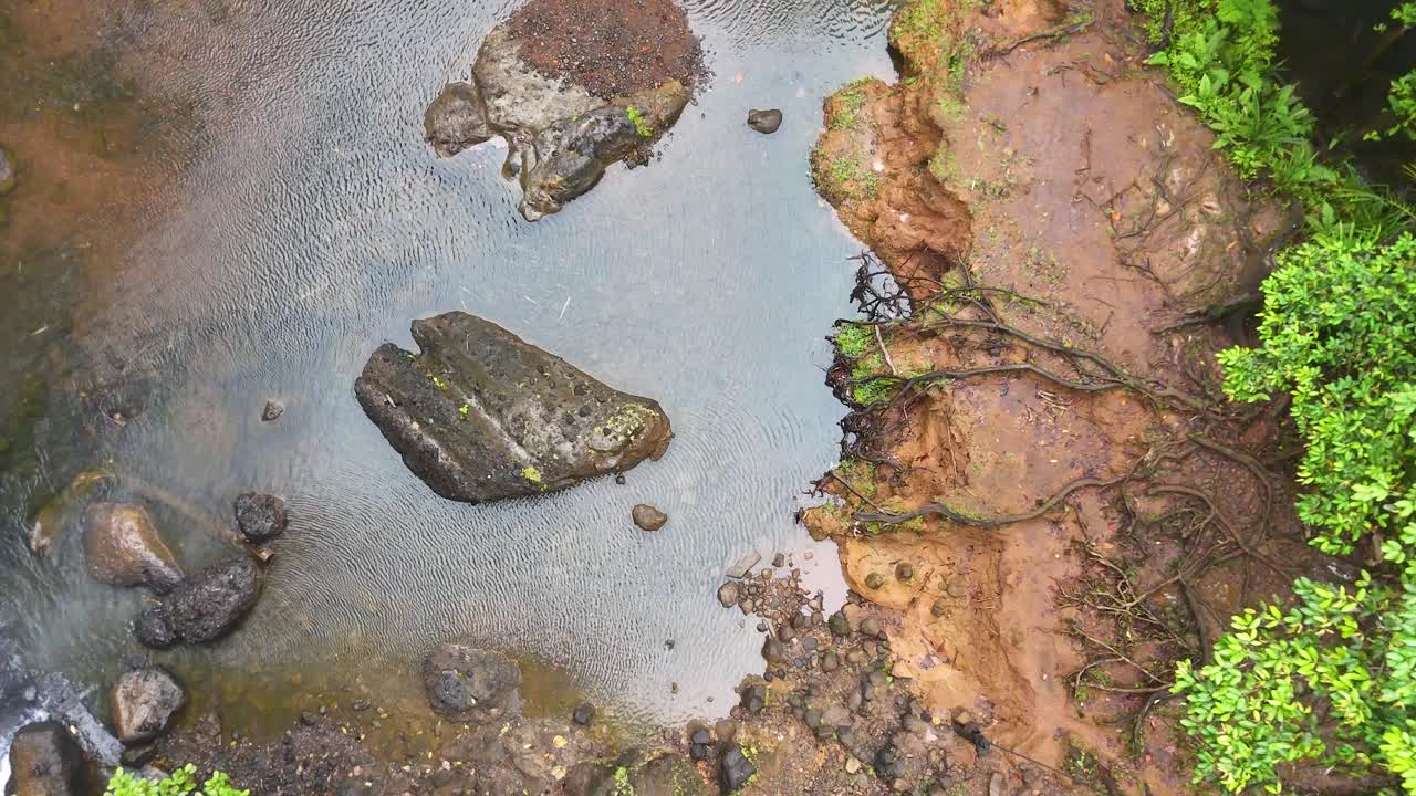 La telecamera di un drone panoramica su un fiume tropicale e un bacino roccioso vicino alla cascata di Ngardmau a Palau
