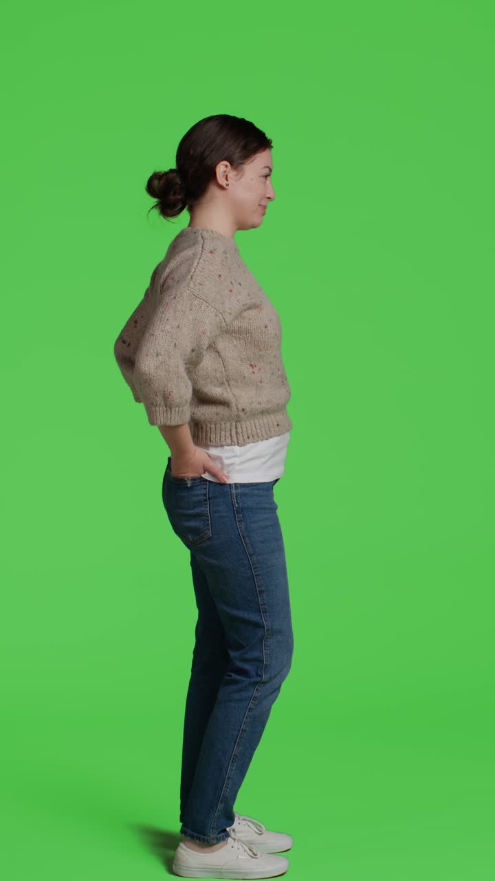 Video verticale: profilo di una donna felice in piedi a figura intera su green screen