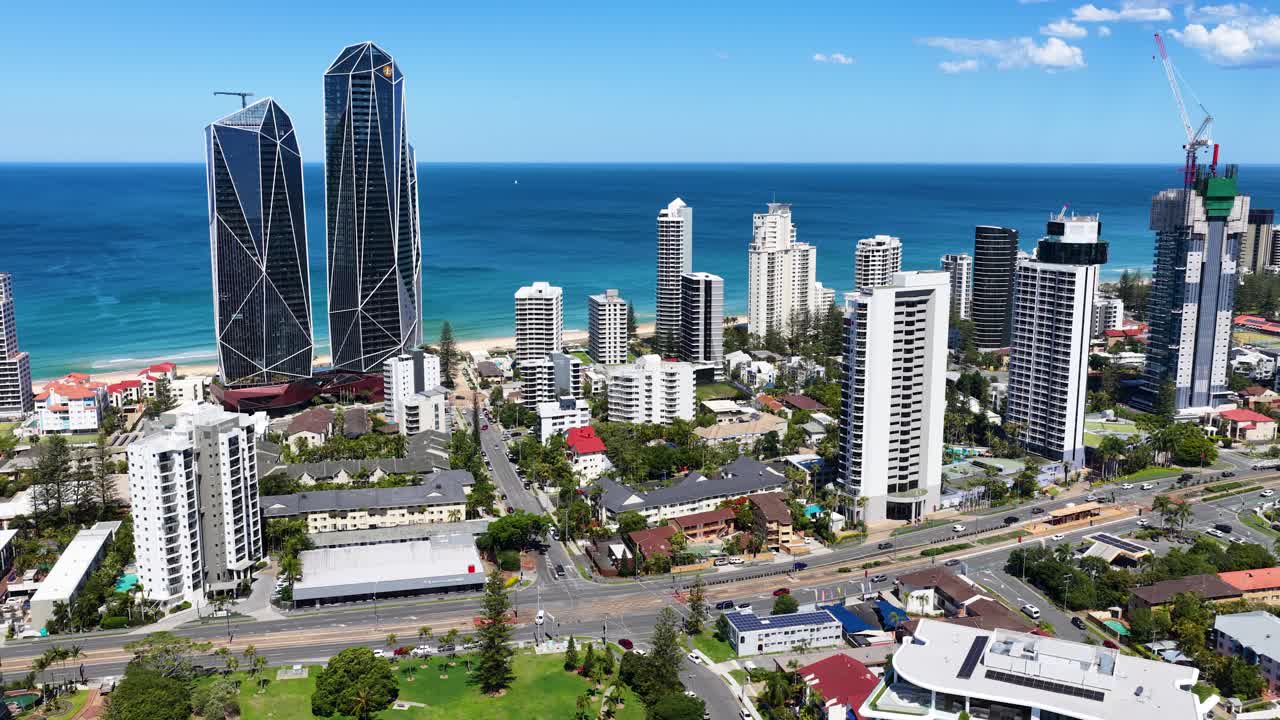 Drone ascends above Broadbeach Waters, revealing modern skyscrapers, coastline, and blue ocean under sunlight