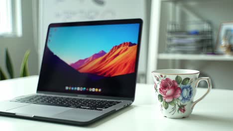 a sleek laptop and colorful cup unite in an inspiring workspace, showcasing a beautiful harmony of technology and personal touches in a modern environment