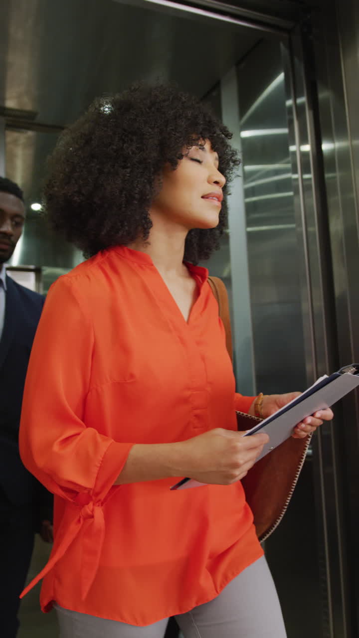 Vertical video of diverse business people taking elevator at office