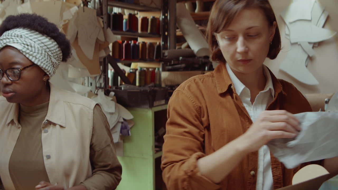 mujeres empacando zapatos hechos a mano en cajas y hablando en talleres
