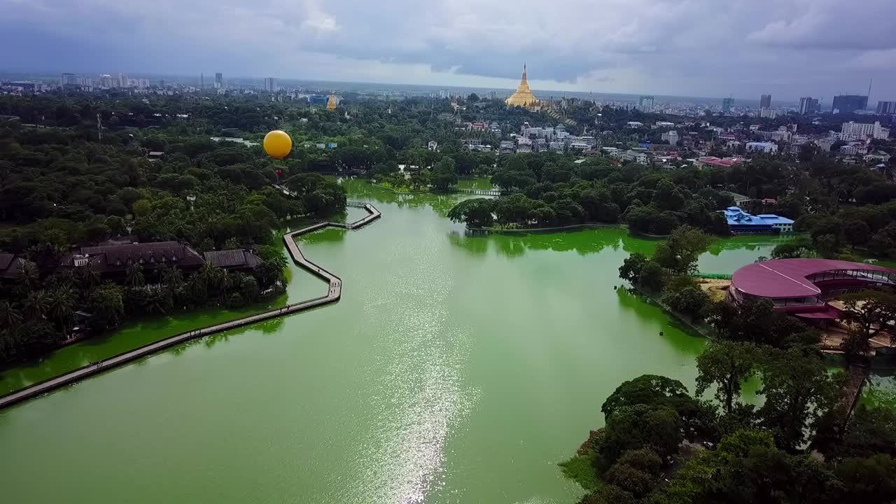 A breathtaking panoramic aerial view showcasing the city of Yangon, the serene Kandawgyi Lake, and the iconic Shwedagon Pagoda in Myanmar, highlighting the beauty and cultural landmarks of the city.