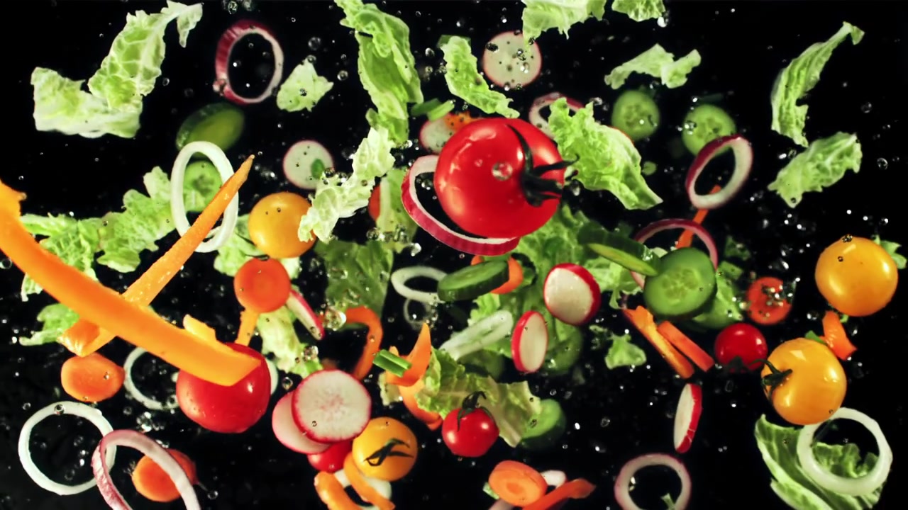 Ripresa al rallentatore di verdure fresche per insalata che cadono con gocce d'acqua.