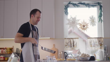 smiling man flipping pancakes in pan while working in kitchen