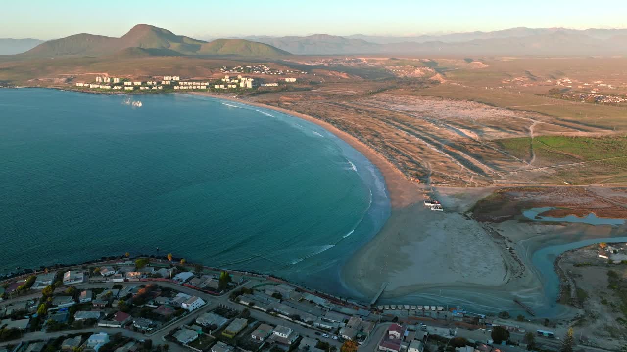 vista aérea panorámica de la playa de socos en el norte de chile, con edificios y casas solitarias en las montañas a los lados, día soleado