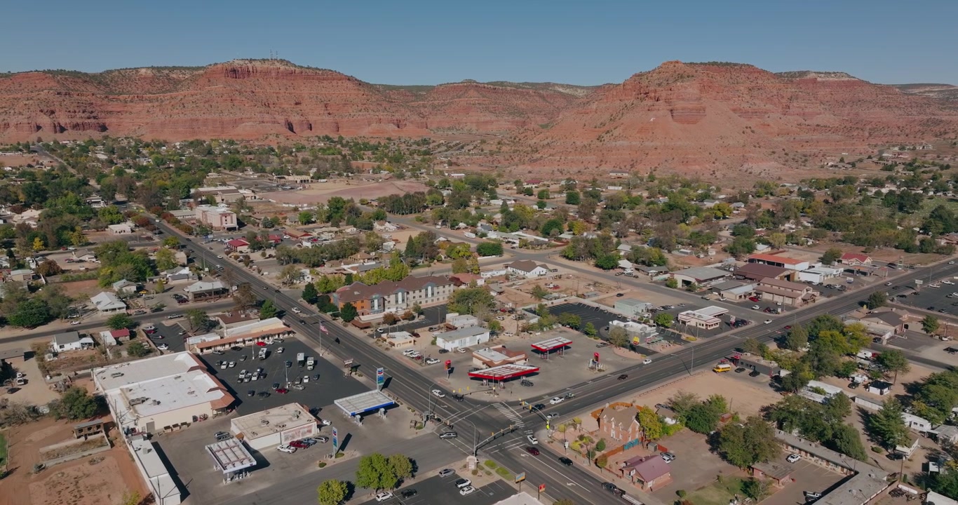 Strade ed edifici del centro di Kanab, Utah, circondati da mesas desertiche di arenaria rossa, panoramica orbitale con drone