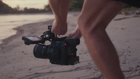 videographer filming on a beach at sunset
