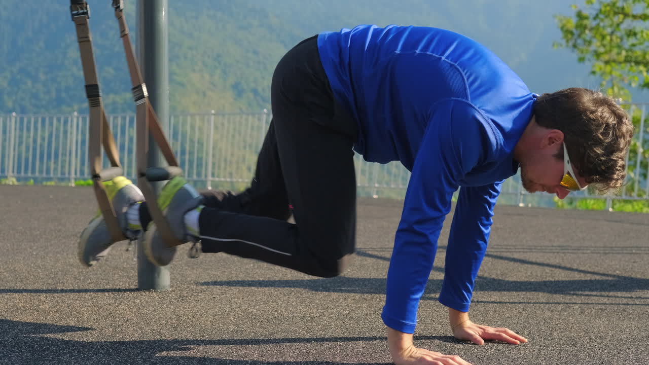야외에서 서스펜션 운동을 하는 남자