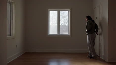 young woman in an empty apartment room looking around