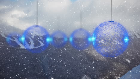 animation of snow falling and christmas baubles over winter landscape