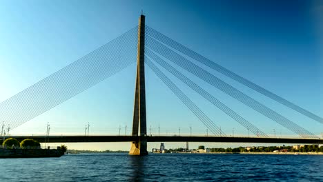 timelapse of traffic on cable bridge in riga with people canoeing nearby