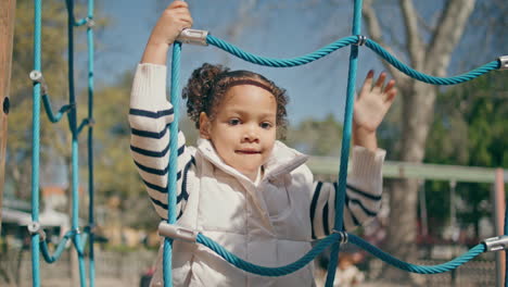 girl climbing rope net at family weekend close up. child playing in park