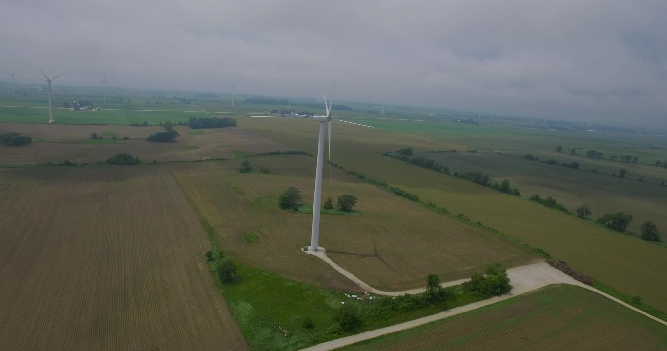 Flying towards wind turbine with aerial drone. Rotating blades. Onshore wind farm. Cloudy day. 4K.