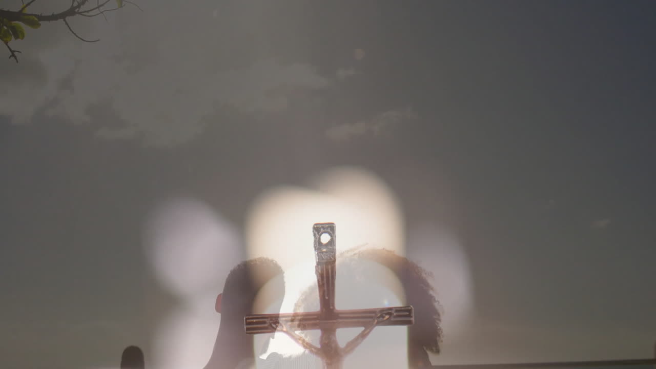 Silhouette of crucifix with blurred lights and dark sky in background