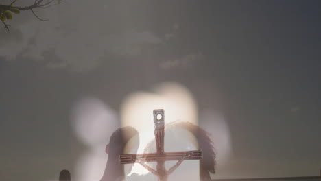 silhouette of crucifix with blurred lights and dark sky in background