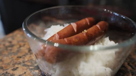 toma de primer plano de huevos fritos colocados en un perrito caliente y harina de arroz en un tazón transparente