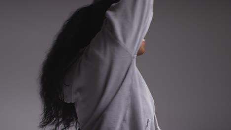 Studio-Portrait-Shot-Of-Young-Woman-Wearing-Hoodie-Dancing-With-Low-Key-Lighting-Against-Grey-Background-14