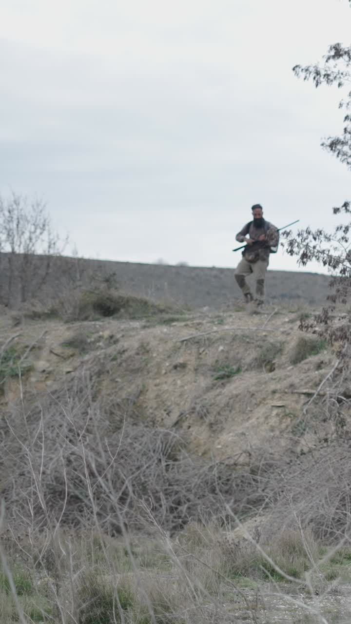 Hunter in camouflage with rifle in a natural landscape