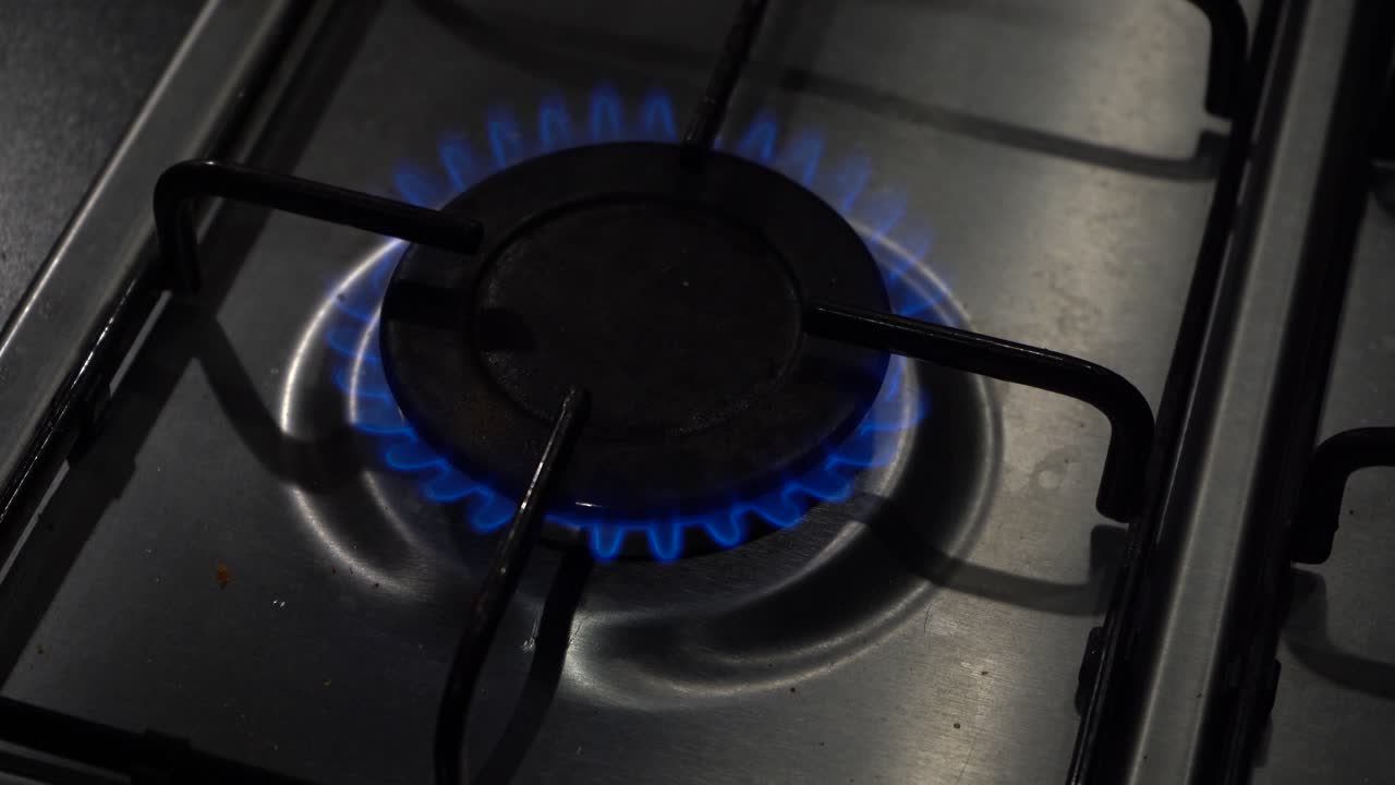 높은 각도 보기:가스 쿡탑 버너가 뜨거운 푸른 불꽃으로 점화됩니다.