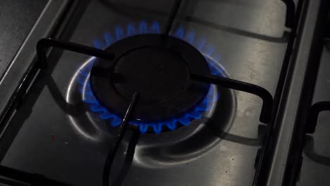 High-angle-view:-Gas-stovetop-burner-ignites-into-hot-blue-flame