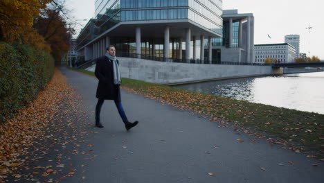man walking by buildings and water