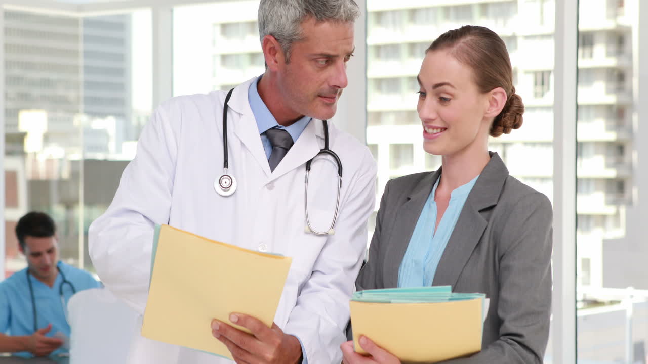 dos médicos mirando a la cámara con sus colegas detrás