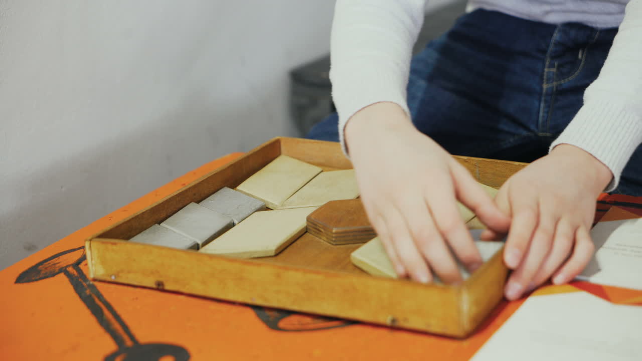 Boy playing with puzzle wooden tangram. Early education concept