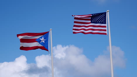 Banderas-De-Puerto-Rico-Y-Estados-Unidos-De-América-Ondeando-Al-Viento-En-Un-Día-Soleado-Con-Nubes-Blancas-Hinchadas