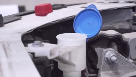 car mechanic is filling up window washer fluid on the maintenance yearly service in the car workshop