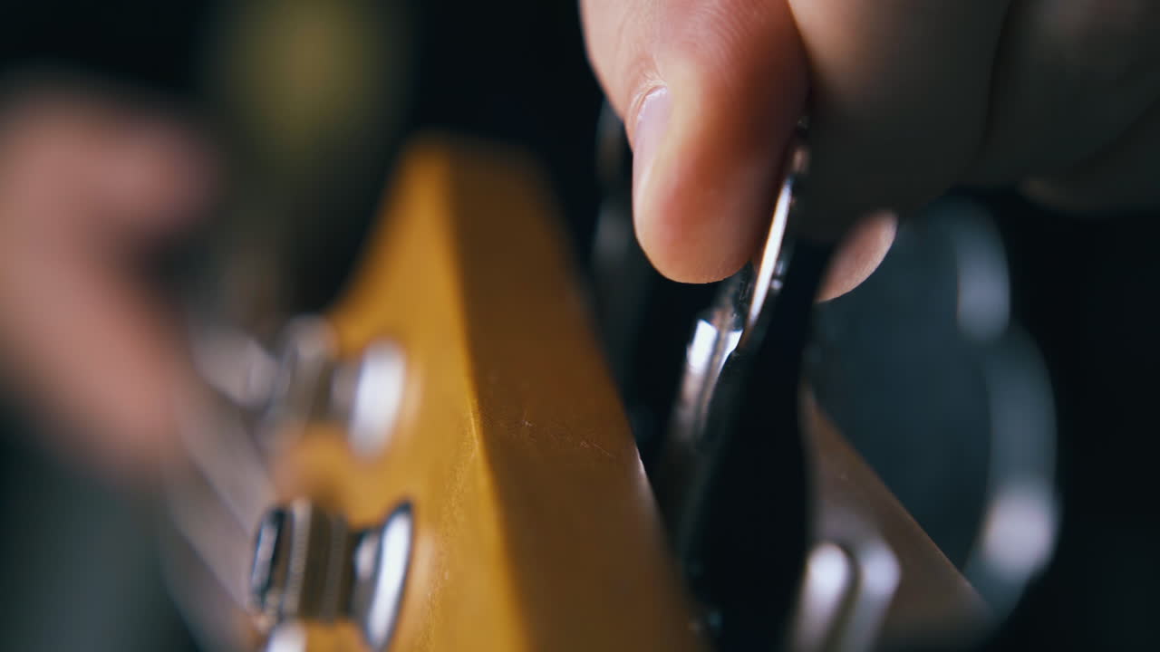 musician hands tune third metal string on modern bass guitar