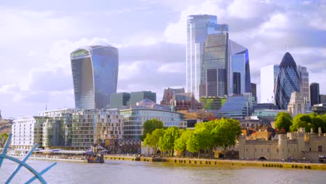 london city skyline and tower of london, landscape view from tower bridge on a sunny summer day with blue sky and light clouds, blue fence