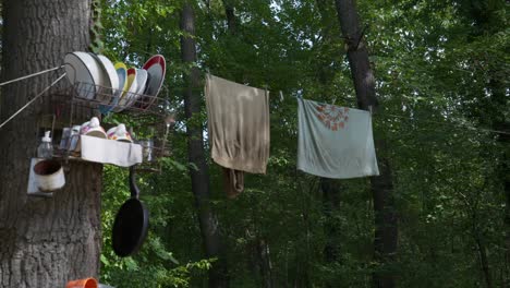 Pan-up-shot-reveal-off-grid-camping-scene-with-kitchen-items-hung-on-trees