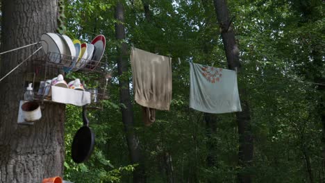 pan up shot reveal off grid camping scene with kitchen items hung on trees