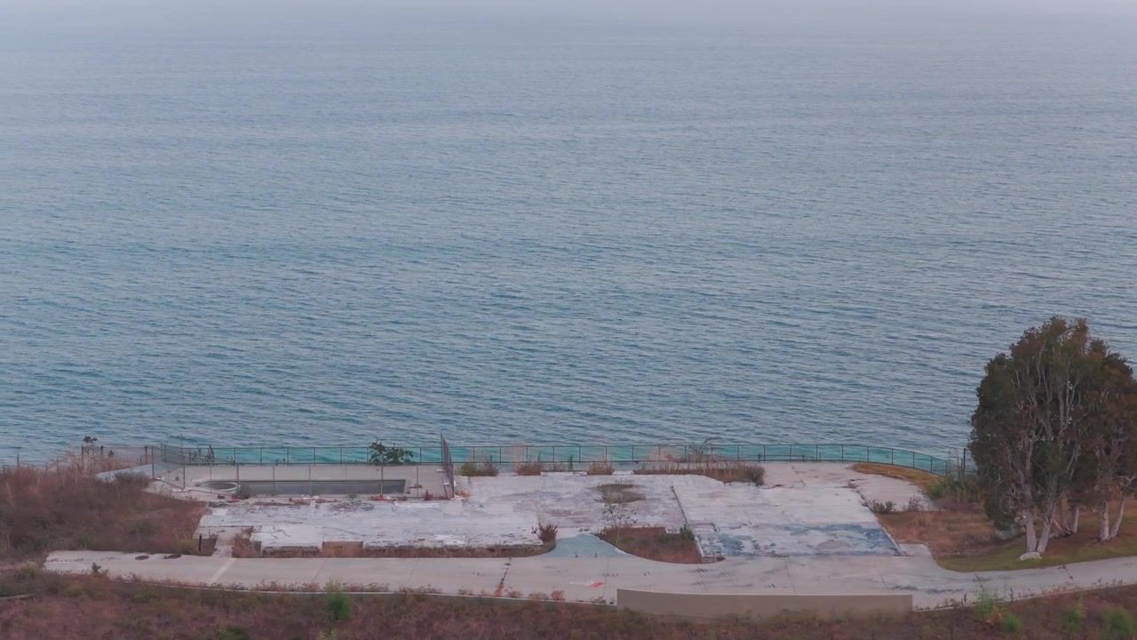 Aerial telephoto panning shot of an abandoned oceanfront property after the wildfire in Malibu, California. 4K