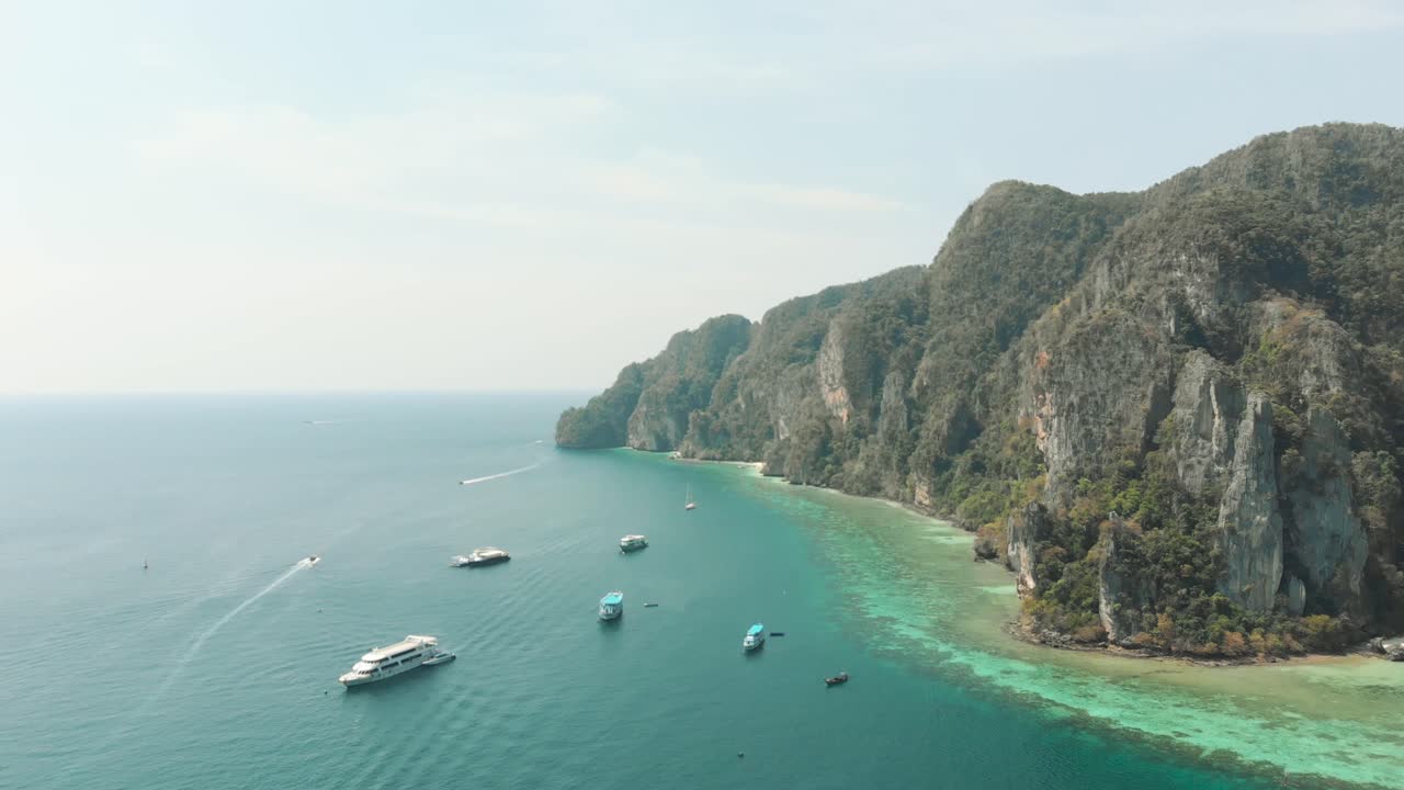 Litorale idilliaco bagnato da calde acque esotiche, delimitato da una scogliera vicino a Pirate Beach Cove, sull'isola di Ko Phi Phi Don, Thailandia - Ripresa aerea.