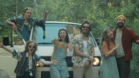 happy friends taking group picture by van in woods