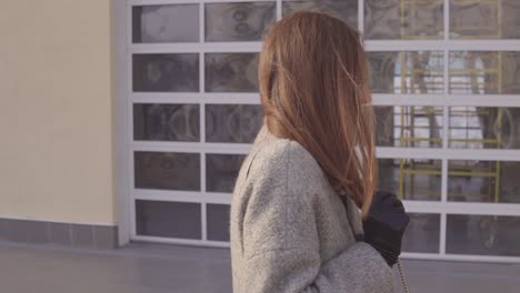 woman in a gray coat outside a modern building