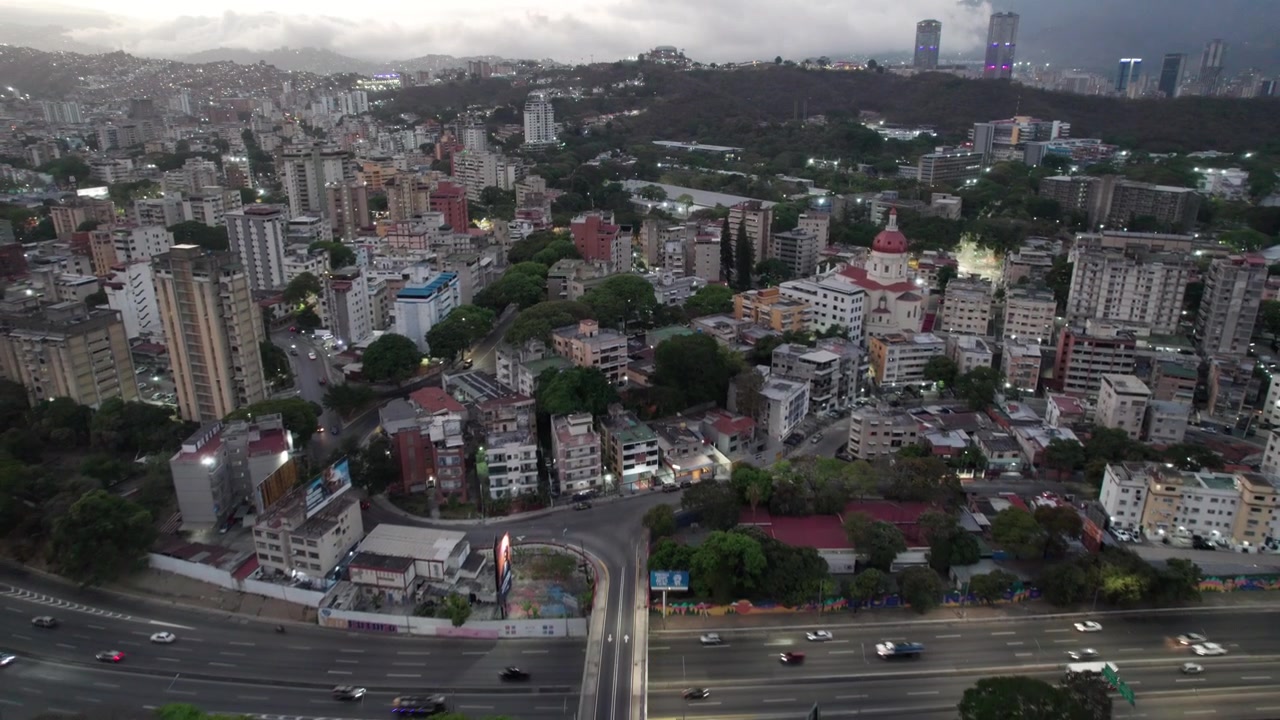 Il drone si allontana sopra il quartiere Los Chaguaramos, mostrando strade ed edifici della città al tramonto