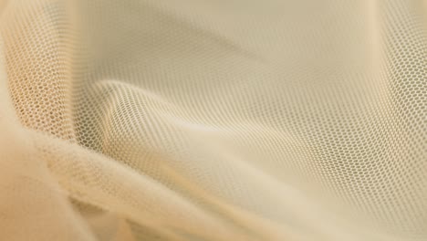 beige fine mesh close-up. sewing a wedding dress. light veil nylon. handmade tailoring, professional clothing concept. abstract background