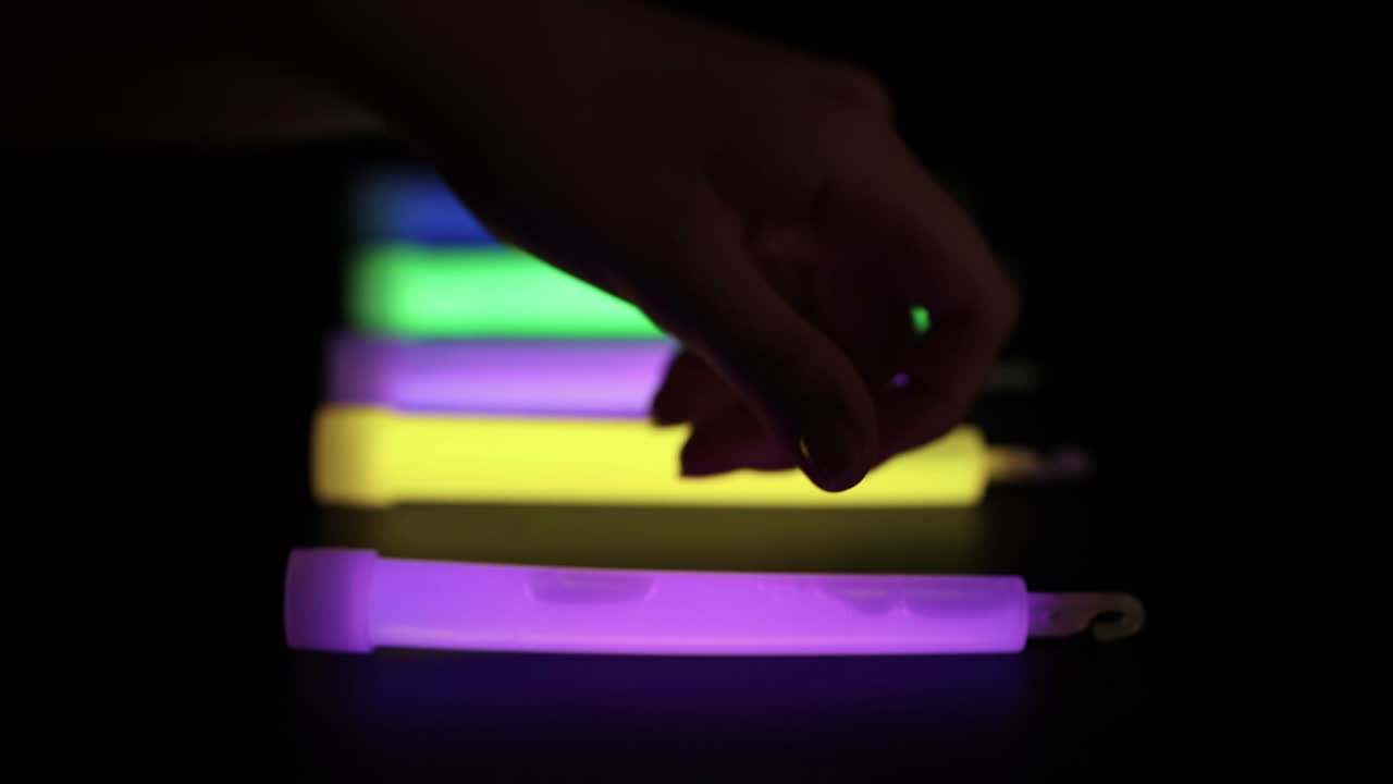manos arreglando palos brillantes en la oscuridad