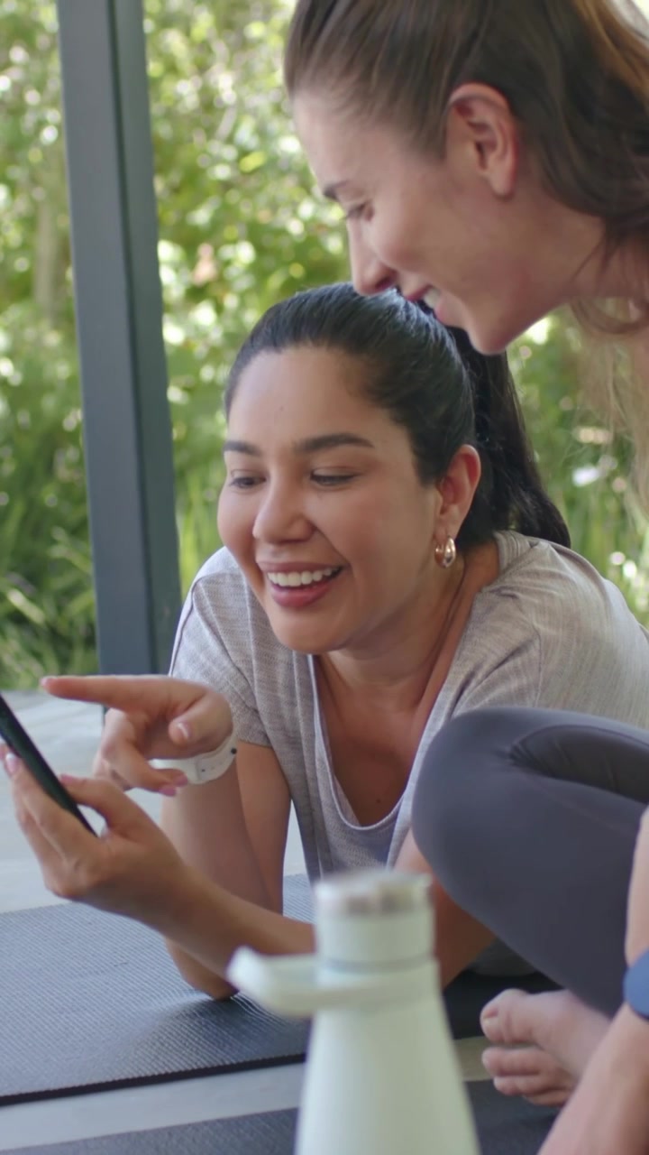 Vertical video: Picking up phone Hispanic woman in gray top tapping and sharing screen on patio