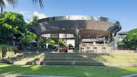 a serene, sunlit luxury resort bar in phuket, thailand, surrounded by lush greenery and modern architecture