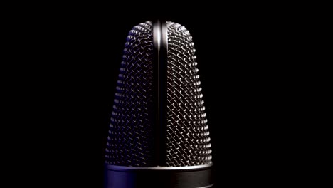 micrófono de estudio profesional girando de cerca sobre un fondo negro