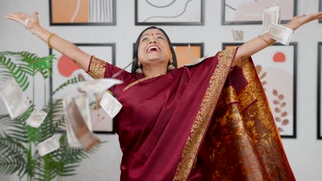 happy indian woman throwing money in air